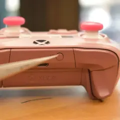 Różowy pad Xbox z różowymi nakładkami na analogach, zbliżenie na przycisk parowania. Dowiedz się, jak podłączyć pada Xbox do PC.