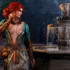Triss Merigold w alternatywnym wyglądzie, w bogato zdobionej sukni, stoi obok kamiennej fontanny.