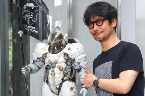 Hideo Kojima, twórca gier wideo, obok postaci z gry w białym skafandrze. Kojima Productions.