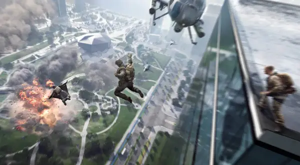 Skoczkowie w kombinezonach wingsuit spadają na miasto, podczas gdy helikopter i wybuchy tworzą chaos. Gra Battlefield 2042 wymaga odpowiedniego sprzętu.