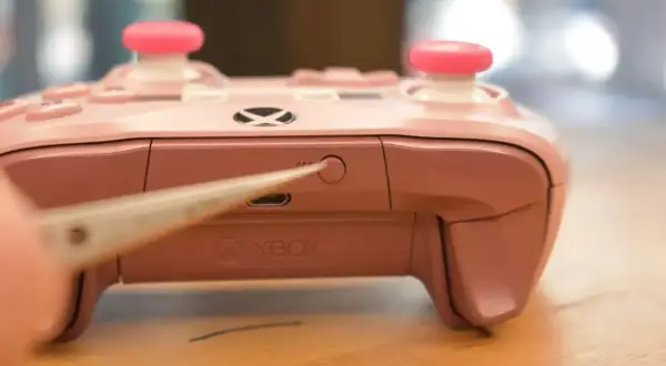 Różowy pad Xbox z różowymi nakładkami na analogach, zbliżenie na przycisk parowania. Dowiedz się, jak podłączyć pada Xbox do PC.