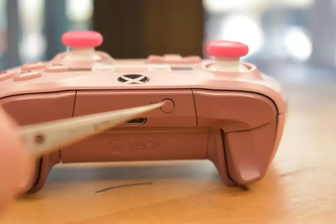 Różowy pad Xbox z różowymi nakładkami na analogach, zbliżenie na przycisk parowania. Dowiedz się, jak podłączyć pada Xbox do PC.