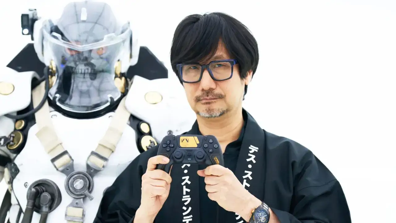 Hideo Kojima, mistrz gier wideo, prezentuje kontroler z motywem Death Stranding. Obok niego stoi postać w futurystycznym skafandrze.