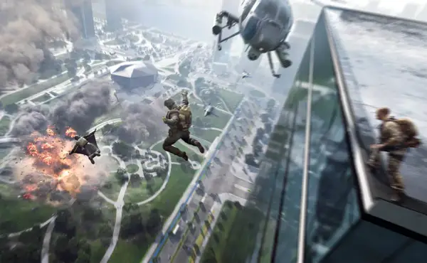 Skoczkowie w kombinezonach wingsuit spadają na miasto, podczas gdy helikopter i wybuchy tworzą chaos. Gra Battlefield 2042 wymaga odpowiedniego sprzętu.