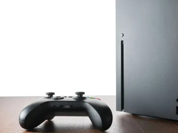 Czarny kontroler Xbox i konsola Series X na drewnianym blacie. Czy gry z Xbox 360 działają na Xbox Series X? Sprawdźmy!